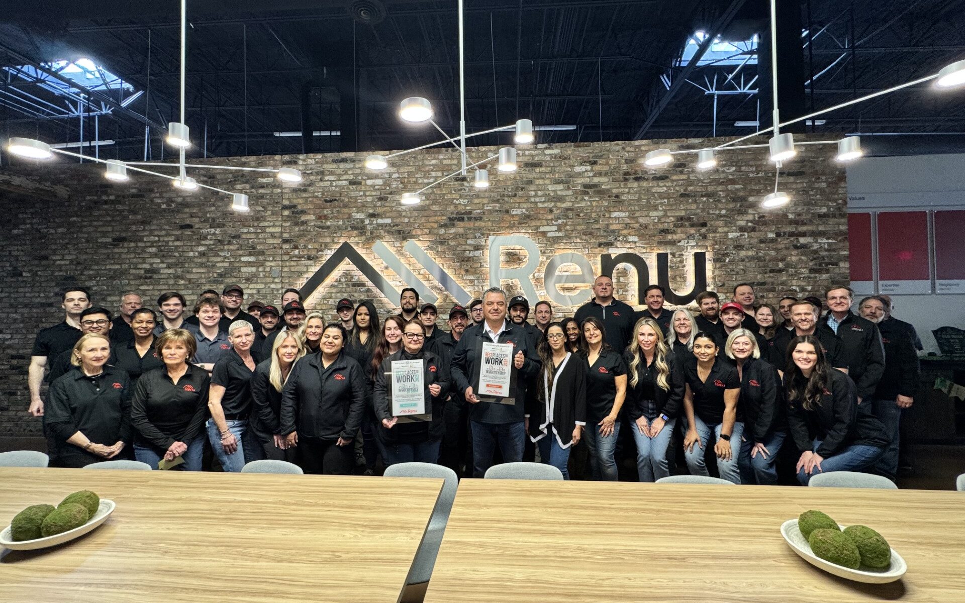Renu employees pose with the Best Places to Work in Multifamily and for Women plaques in the Renu office